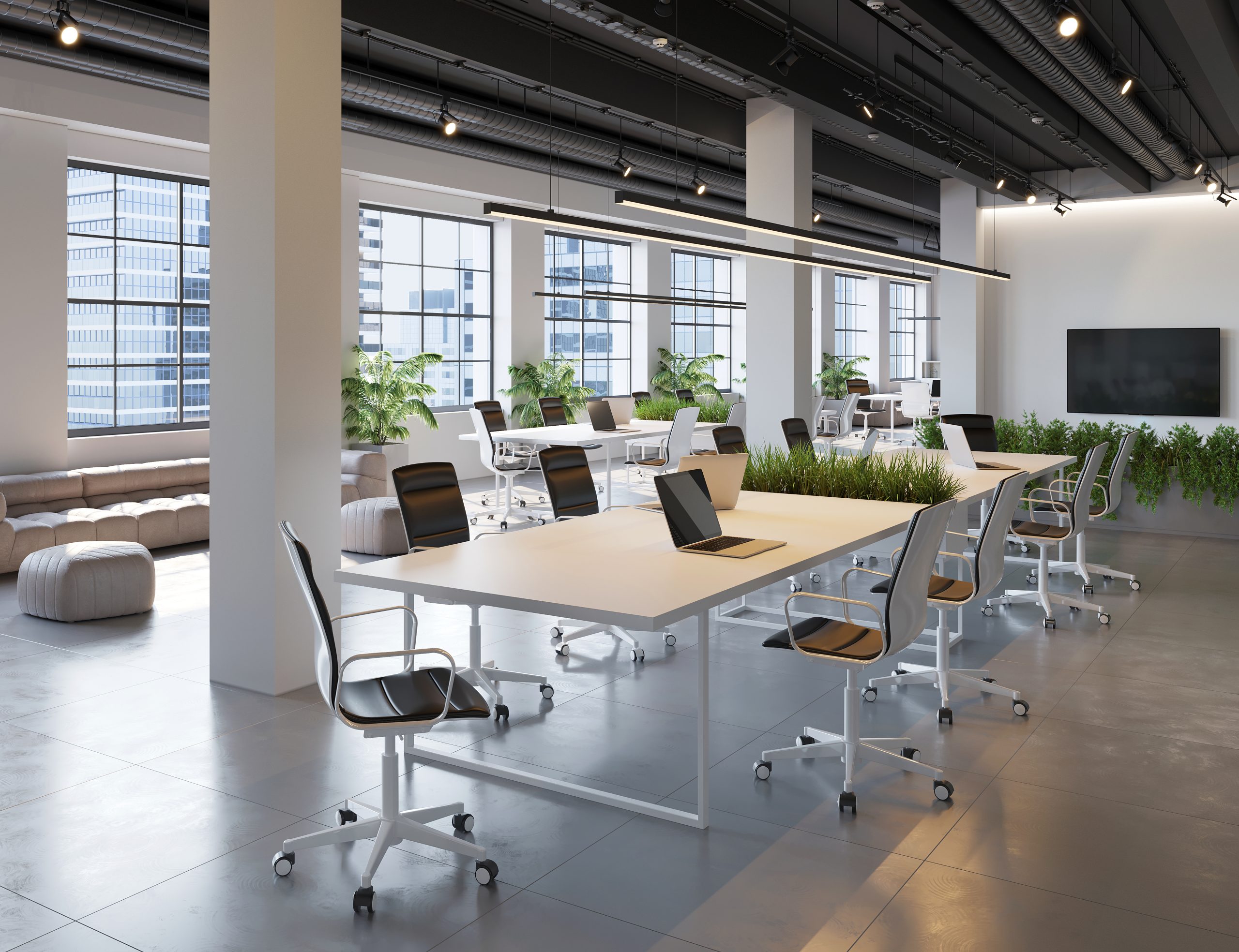 Bright modern corporate conference room table with laptops, architectural plans, and large glass windows filled with natural light.